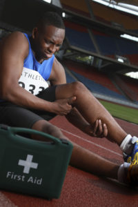 Male-athlete-lying-on-track-clasping-leg-in-pain